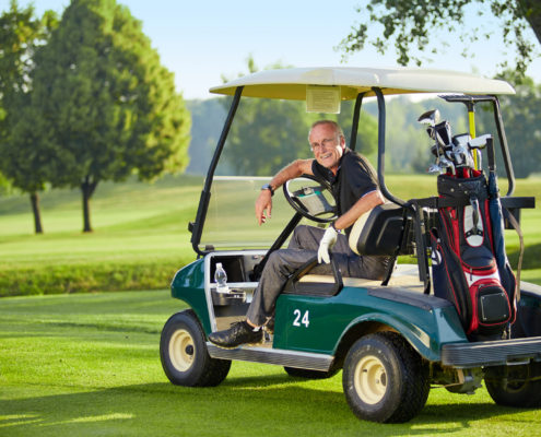 Mature man sitting in a golfcart on the green